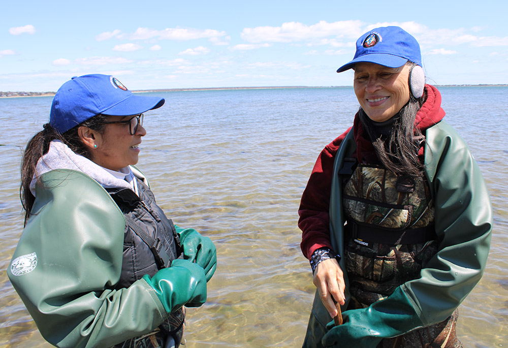 Vestidas con indumentaria impermeable, dos miembros de Shinnecock se acercan a la costa para inspeccionar las algas. 