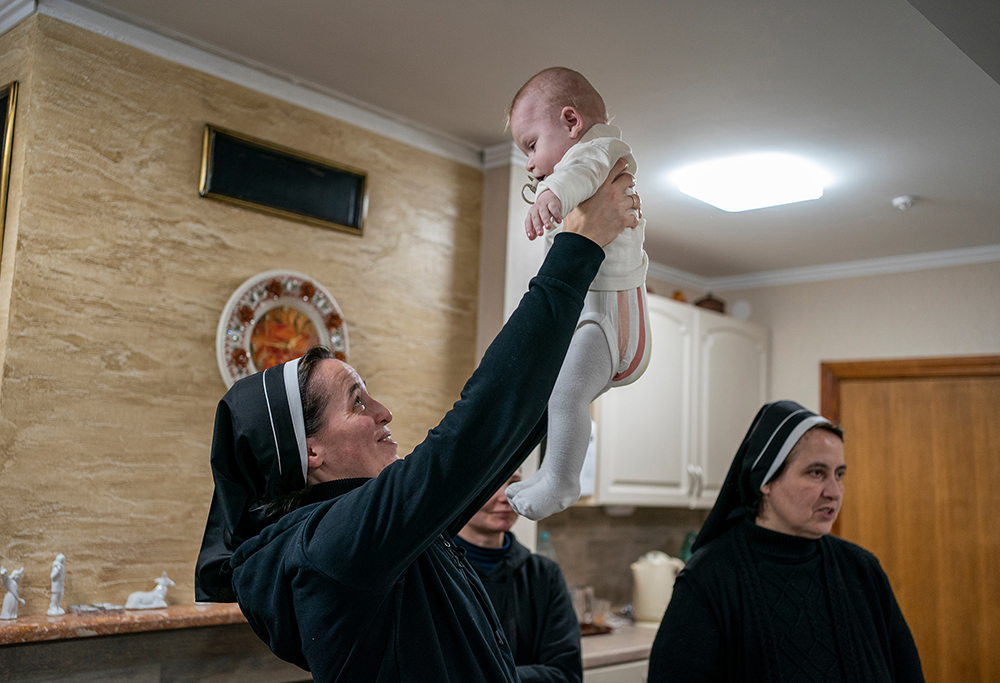 Sr. Veronika Yaniv of the Sisters Catechists of St. Anne holds up a baby at the sisters' monastery outside of Lviv, Ukraine, which is currently home to six mothers, seven children and six retirees. (GSR photo/Gregg Brekke)
