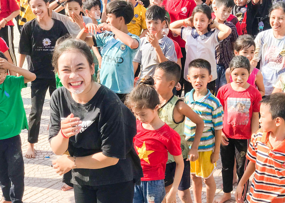 Lovers of the Holy Cross Sr. Lucia Phung Thi My Tien (in black) smiles broadly while playing games with some 100 orphans at Cua Viet Beach in Quang Tri province Sept. 23. "They swim, play football and other games, and draw pictures as a way to discover the environment and relax," she said. (GSR photo/Joachim Pham)