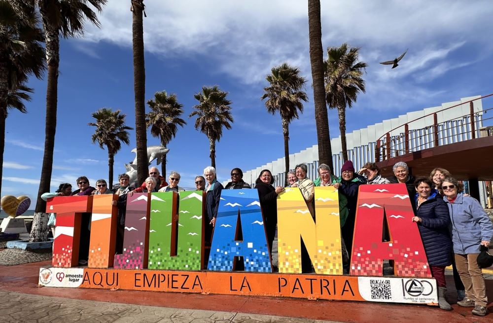 Pilgrimage group poses with large sign that says "Tijuana."