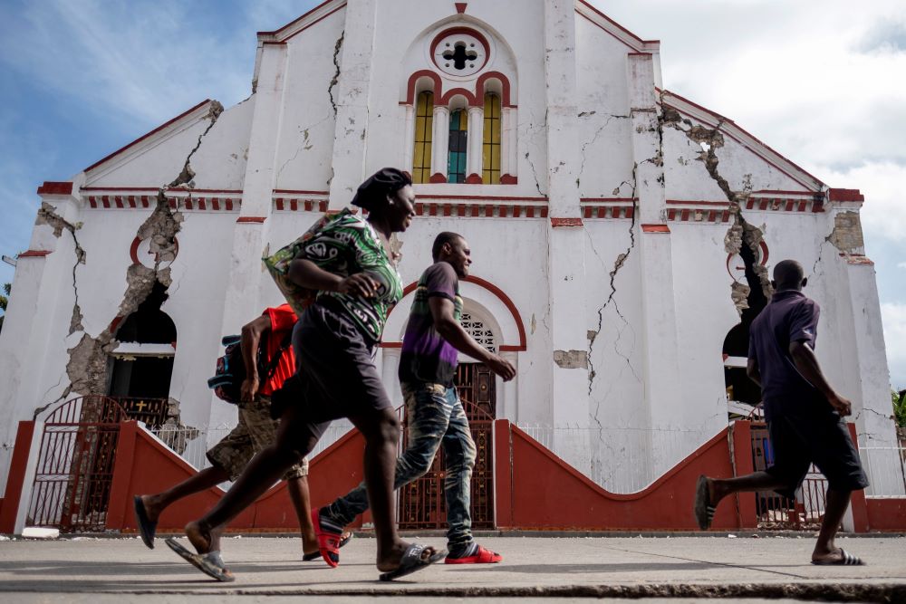 People run past a heavily damaged church in Les Cayes, Haiti, Aug. 18, after a 7.2 magnitude earthquake rocked the area four days earlier. (CNS/Reuters/Ricardo Arduengo)