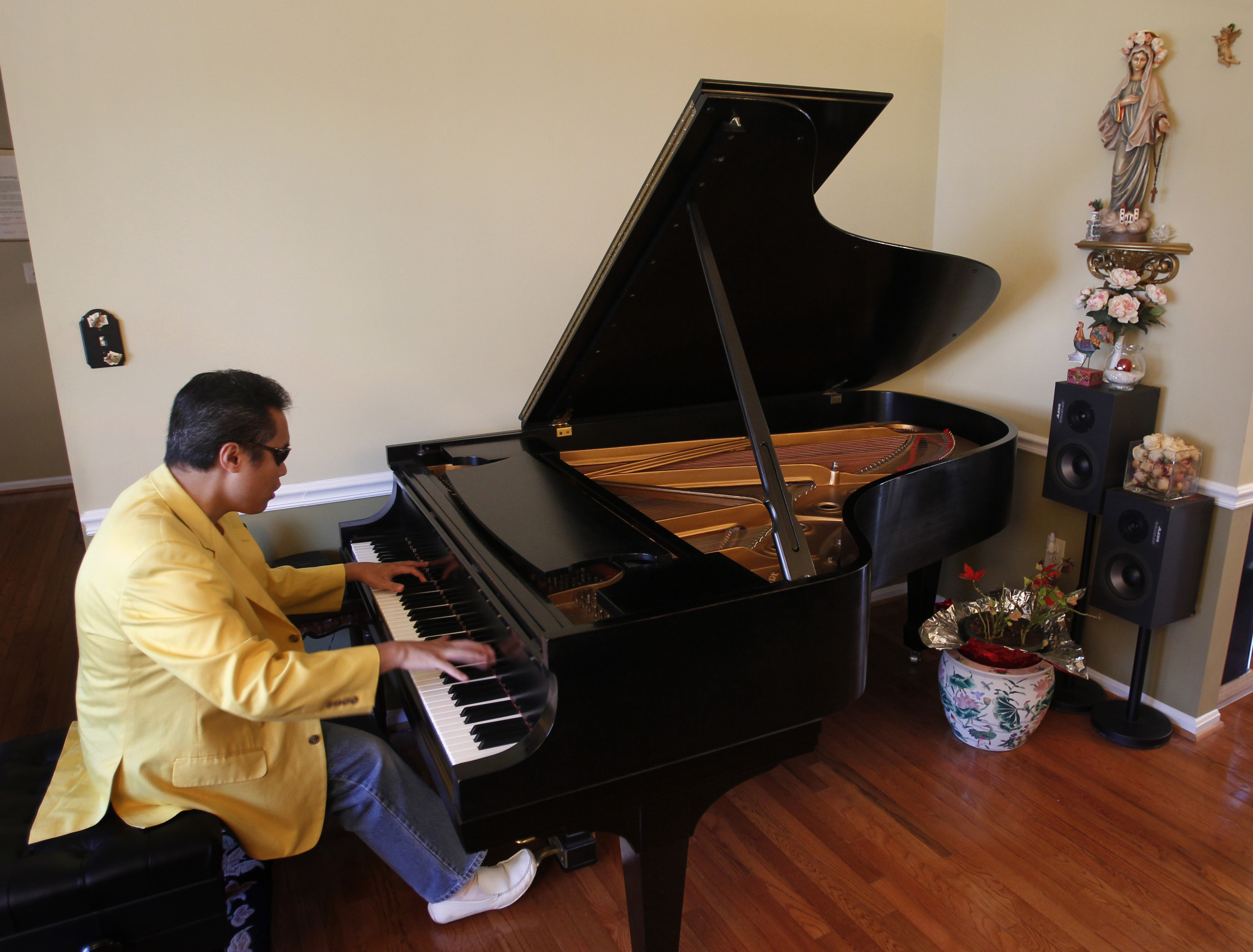 Pianist and tenor Carlos Ibay performs at his home in Fairfax, Va., April 9. Ibay, known as "Chucky," is in music ministry at his Catholic parish, St. Michael in Annandale, Va. He was born premature and spent the first three months of his life in an incu bator, where he lost his sight because of too much oxygen. (CNS photo /Bob Roller)