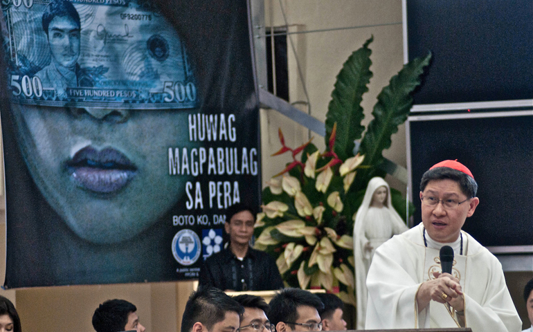 Cardinal Luis Antonio Tagle blesses the command center of the unofficial parallel count of the Parish Pastoral Council for Responsible Voting, where a tarp displays its anti-vote-buying campaign slogan, "Do not be blinded by money." (Roy Lagarde)