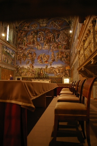 The cardinals will deliberate from these chairs inside the Sistine Chapel over who will be the next pope. They will be flanked by Michelangelo's painting of the last judgment, seen in the background. (NCR photo/Joshua J. McElwee)