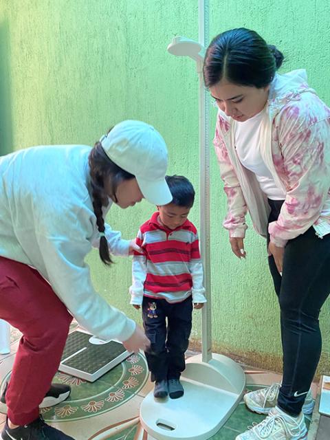 Nutrition majors Vallery Roberts and Shania Salinas measure a child in Santa Apolonia, during a solidarity and service trip to Guatemala. (Courtesy of Martha Ann Kirk)