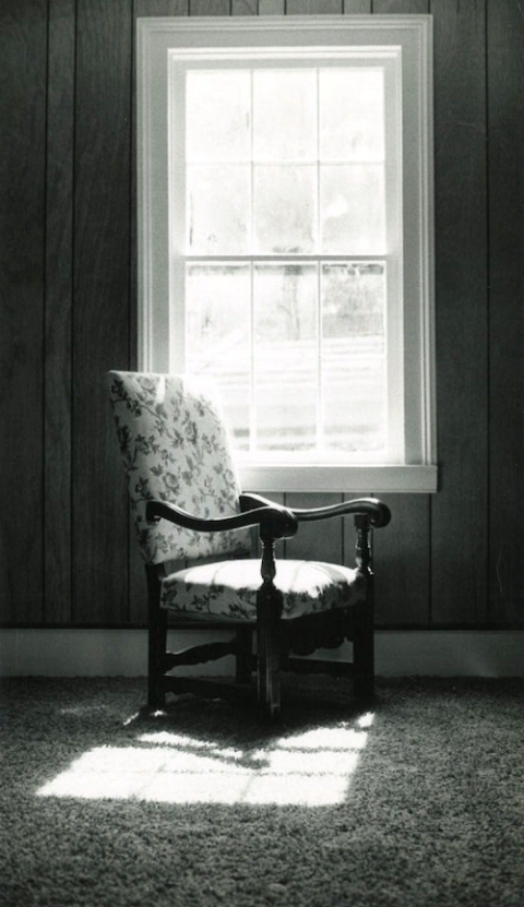 vertical black and white upholstered chair by window with light falling on floor