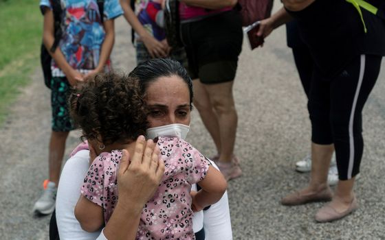 A migrant mother from Venezuela embraces her child as they wait to be transported by Border Patrol after crossing the Rio Grande into Del Rio, Texas, May 27, 2021. (CNS/Reuters/Go Nakamura)