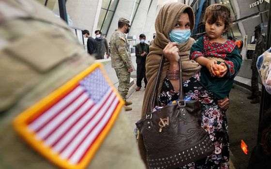 Upon their arrival, Afghan refugees board a bus at Dulles International Airport Sept. 1 in Dulles, Virginia, taking them to a processing center. (CNS/Reuters/Kevin Lamarque)