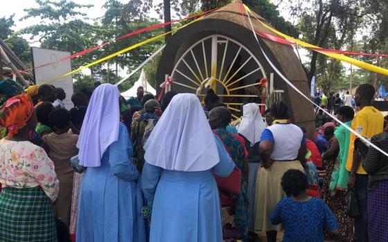 Catholic sisters in blue habits stand alongside other pilgrims as they face the shrine of St. Charles Lwanga at Namugongo. Ribbons in papal colors — white, yellow and red — decorate the site as thousands visit to commemorate the courage and sacrifice of the Uganda martyrs. (GSR photo/Gerald Matembu)