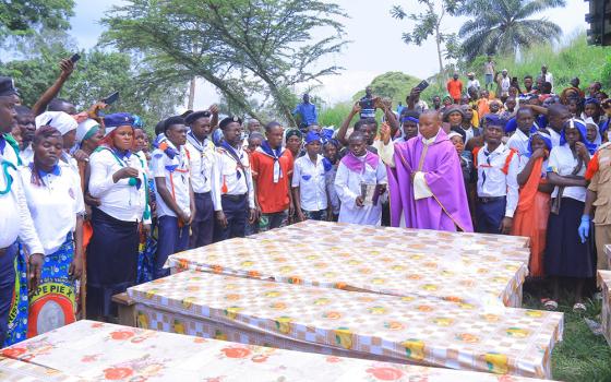 Fr. Aime Lokana Dhego sprinkles holy water on caskets during a funeral Mass in Komanda, in Congo's province of Ituri, July 28, for victims of a horrific attack on the Catholic church in Komanda. At least 40 faithful were shot or killed with machetes during an overnight vigil in the church July 27. (OSV News/Courtesy of Fr. Justin Zanamuzi)