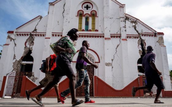 People run past a heavily damaged church in Les Cayes, Haiti, Aug. 18, after a 7.2 magnitude earthquake rocked the area four days earlier. (CNS/Reuters/Ricardo Arduengo)