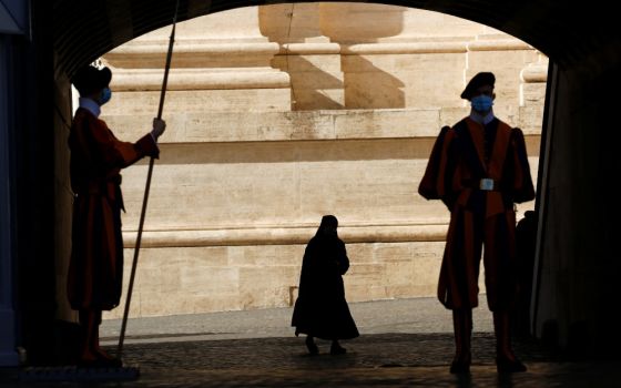 Swiss Guards stand at attention as a nun passes by at the Vatican Nov. 9, 2020. (CNS/Reuters/Remo Casilli)