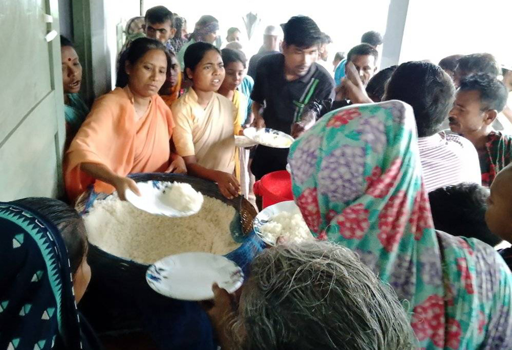 Srs. Sukriti B. Gregory and Lucky Soren, both of Our Lady of the Missions, distribute rice to cyclonic storm Remal victims on May 26 at their school. (Courtesy of Sr. Sukriti B. Gregory)