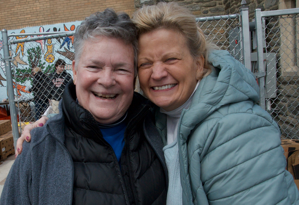 Sr. Bonnie McMenamin (left), a Sister of St. Joseph of Philadelphia and director of the SSJ Neighborhood Center, hugs Bea Russell, the center's advisory board vice president, during the center's monthly food distribution day, March 20. (GSR photo/Dan Stockman)