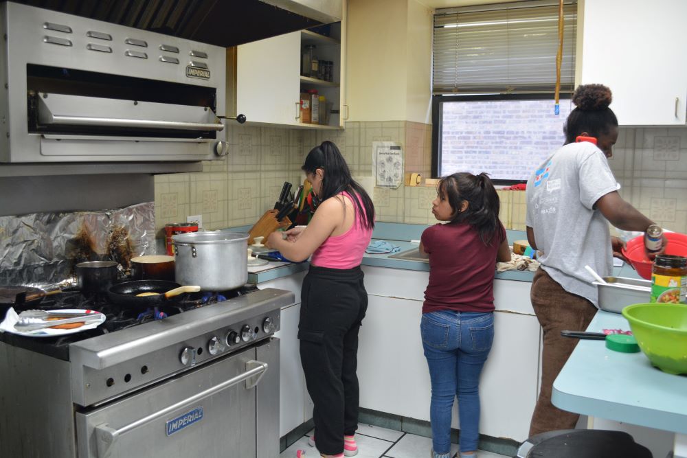 Young women from Latin America and Africa work in the kitchen during after-school hours at Bethany House of Hospitality for 18- to 25-year-old refugee women May 7. 