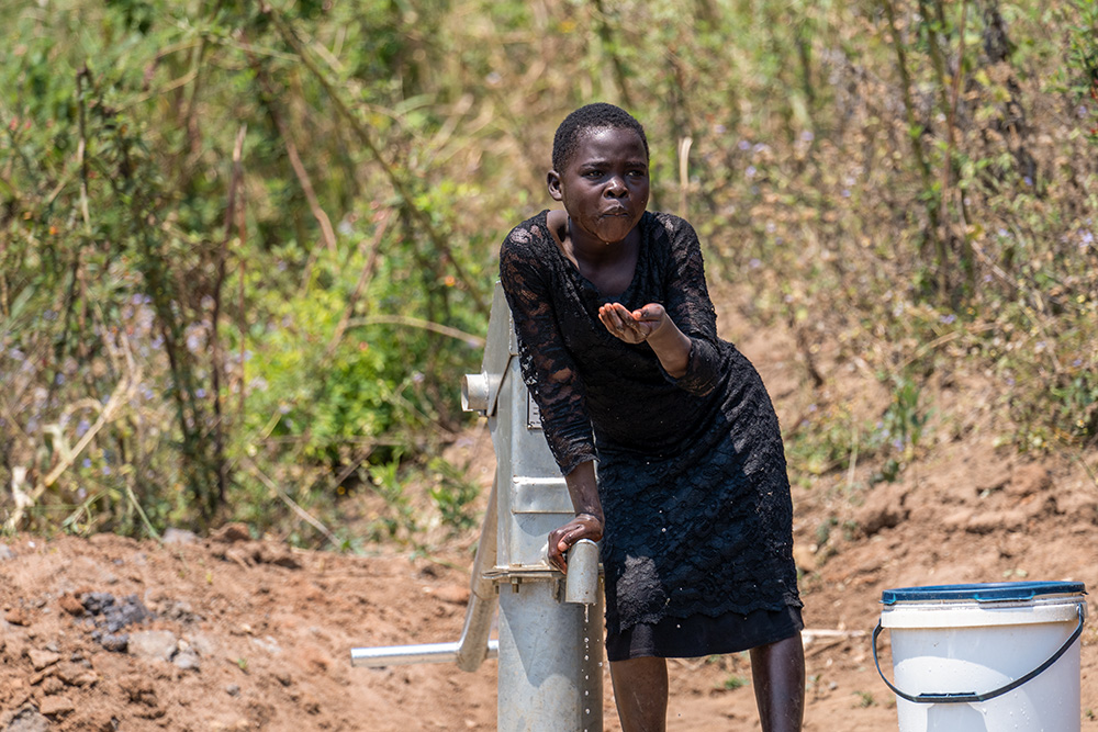 Una joven bebe de la bomba de agua instalada en la aldea de Mphatso, en Malawi, el 1 de octubre de 2021. (Foto: cortesía Mónica Ichife)