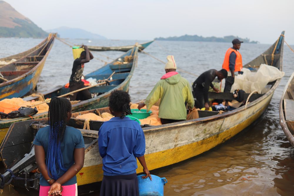 Young women on the shores of Lake Victoria in western Kenya are buying fish as boats return from fishing on July 17. 