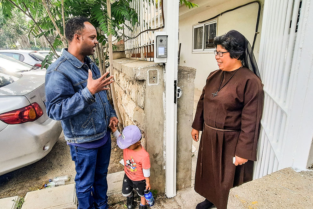 Franciscan Sister of the Eucharist Sr. Maria David Magbanua speaks with Abraham Rada as he comes to pick up his 2-year-old son Yonatan from the St. Rachel Center day care in Jerusalem after a day of work at a nearby minimarket. Rada, who arrived in Israel as a refugee from Eritrea in 2008, says the nuns at St. Rachel take care of Yonatan "like family." (Judith Sudilovsky)