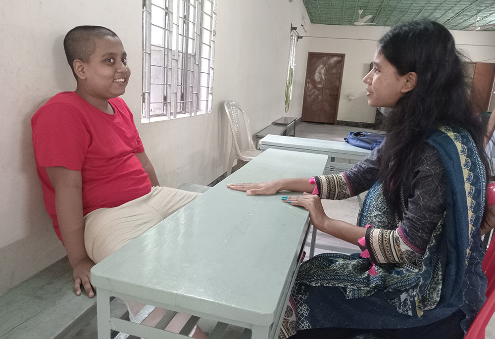 Antora Roy teaches songs to Mohammadulla, 12, an autistic child. He joined the center in February 2024. When he first came to the center, he was hyperactive, unable to listen to teachers. Today, he happily sits and enjoys class. (Sumon Corraya)