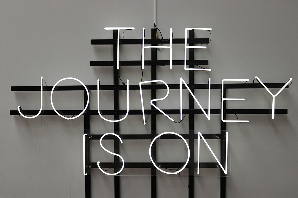 A white neon sign that reads "The journey is on" (Unsplash/Clemens Van Lay)