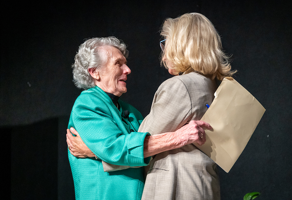 Sr. Joan Chittister and former Wyoming Republican Rep. Liz Cheney greet each other on the stage at the Bayfront Convention Center, Oct. 17 in Erie, Pennsylvania. (NCR photo/ Rick Klein)