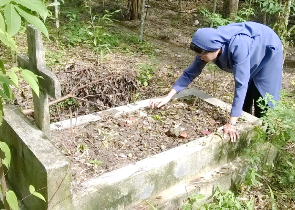 Sr. Martha Tran Thi Toan removes weeds from a neglected grave. 