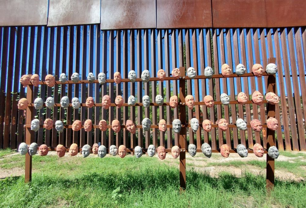 Sculpted papier-maché faces hang on the border wall in Nogales Sonora, Mexico. 