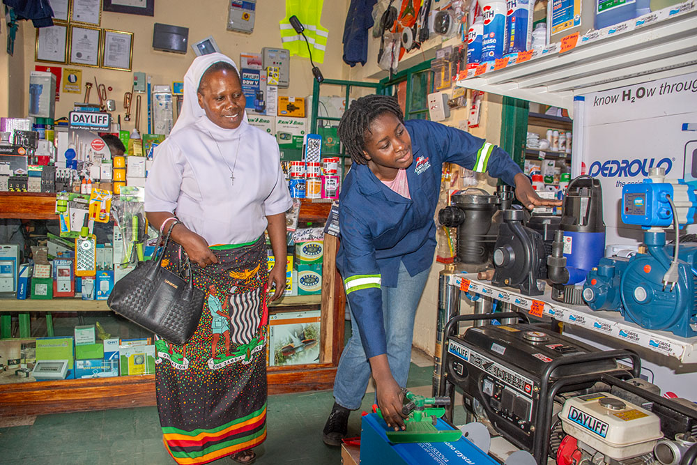 Elizabeth Namfukwe, a beneficiary of Youth Community Training Centre in Livingstone, Zambia, demonstrates how electrical appliances operate at her workplace as Baptistine Sr. Evelyn Bwalya looks on. (Derrick Silimina)