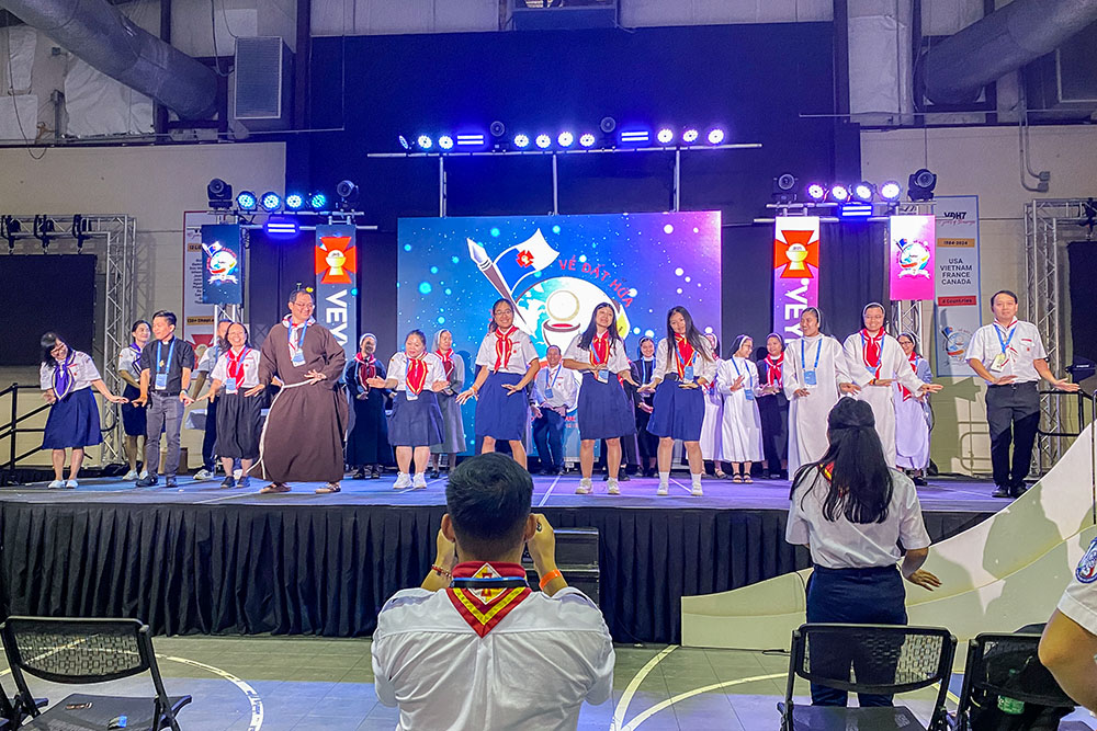 Sisters from various communities join with clergy and the VEYM Spirit Team in the "Hãy Theo Thầy" song and dance before a keynote session. (Catherine Teresa Bui)