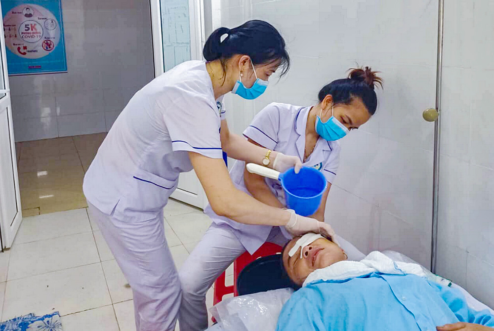 Two lay members of the Lovers of the Holy Cross Association wash a patient's hair at Quang Tri General Hospital on Aug. 10. (Joachim Pham)