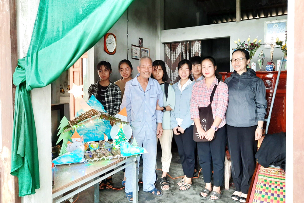 Daughters of Our Lady of the Visitation Sr. Anna Tran Thi Bich Thuy, right, and postulants offer cash, rice and a small nativity scene to Stephanus Duong Quang Vieng, a flood victim, on Dec. 19 in Thua Thien Hue province. (Joachim Pham)