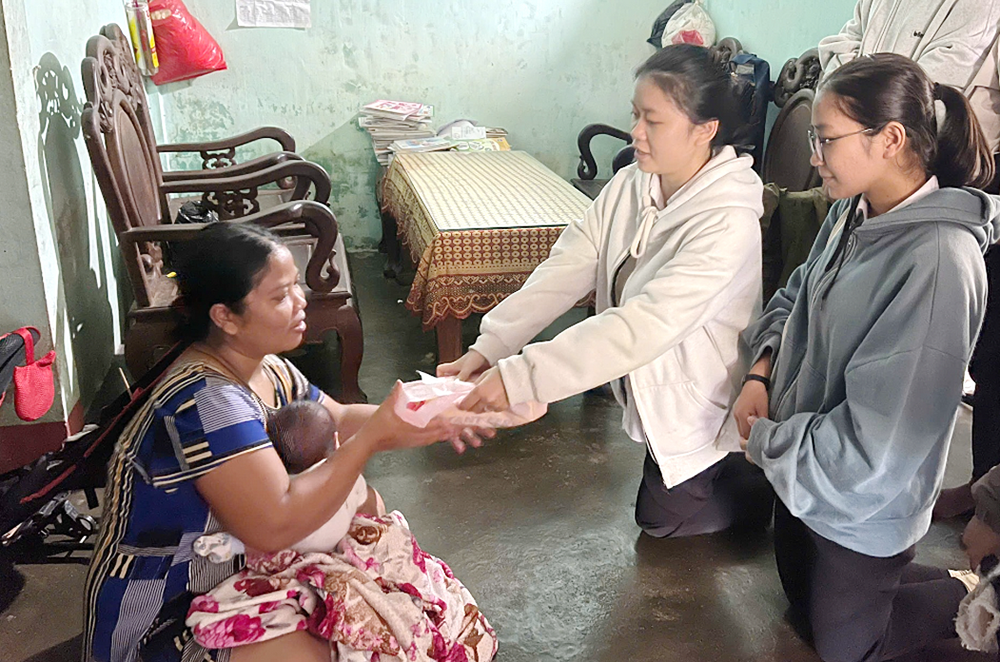 Lovers of the Holy Cross of Hue Sr. Agnes Pham Thi Men, center, gives gifts to Van Kieu ethnic Ho Thon on Dec. 16 in Quang Tri province. Thon said, "I am grateful to the sisters for providing rice and financial support to help me care for my children." (Joachim Pham)