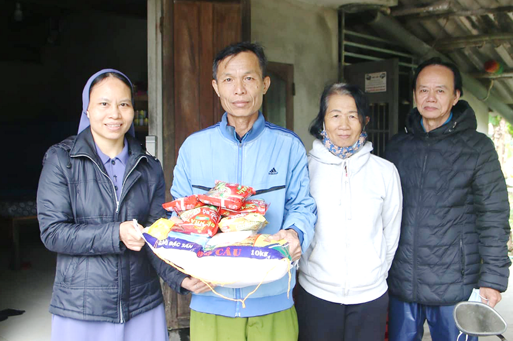 Lovers of the Holy Cross of Hue Sr. Truong Thi Thanh, left, and a volunteer, right, deliver rice and instant noodles to Le Phu Binh and his wife in Hue on Dec. 17. They became unemployed due to bad weather. (Joachim Pham)