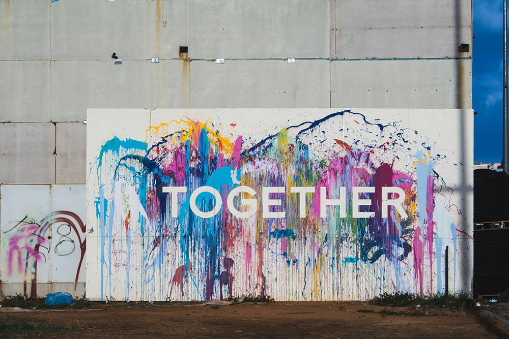 A white sign that says "Together" in white letters on splashes of colors (Unsplash/Nicole Baster)