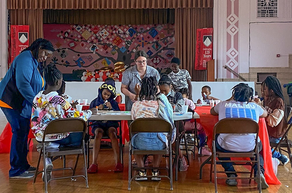 United Stand staff members Michelle Streety (left) and Monica Kaczmarczyk (center) assist children with an activity during one of the nonprofit’s afterschool programs. (Courtesy of United Stand)