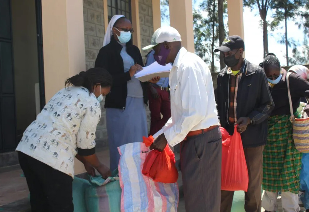 An Assumption sister assists Sr. Florence Muia in supervising food distribution to clients in Upendo Village, northwest of Nairobi, the capital of Kenya. (Courtesy of Upendo Village)