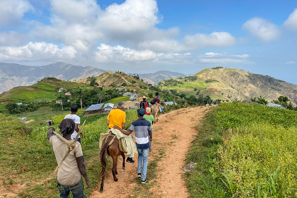 Haitian parishioners from Our Lady of the Assumption Church and Ken Firling (on the mule), a member of St. Margaret Mary Catholic Church in Winter Park, Fla., make a three-hour journey by foot and hoof to one of the Haitian parish's outlying chapels, Our Lady of Mercy. These chapels only see their pastor once a month for Mass. The rest of the time they have an administrator who conducts prayer services and oversees other parish activities. (Courtesy of St. Margaret Mary Church)