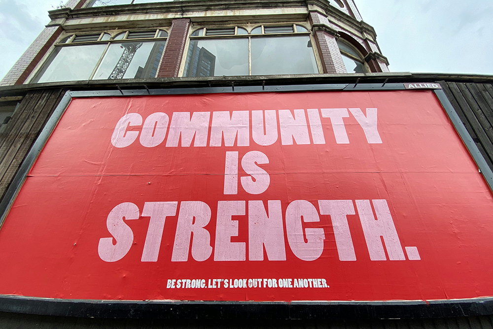 A sign that reads "Community is strength" (Unsplash/John Cameron)