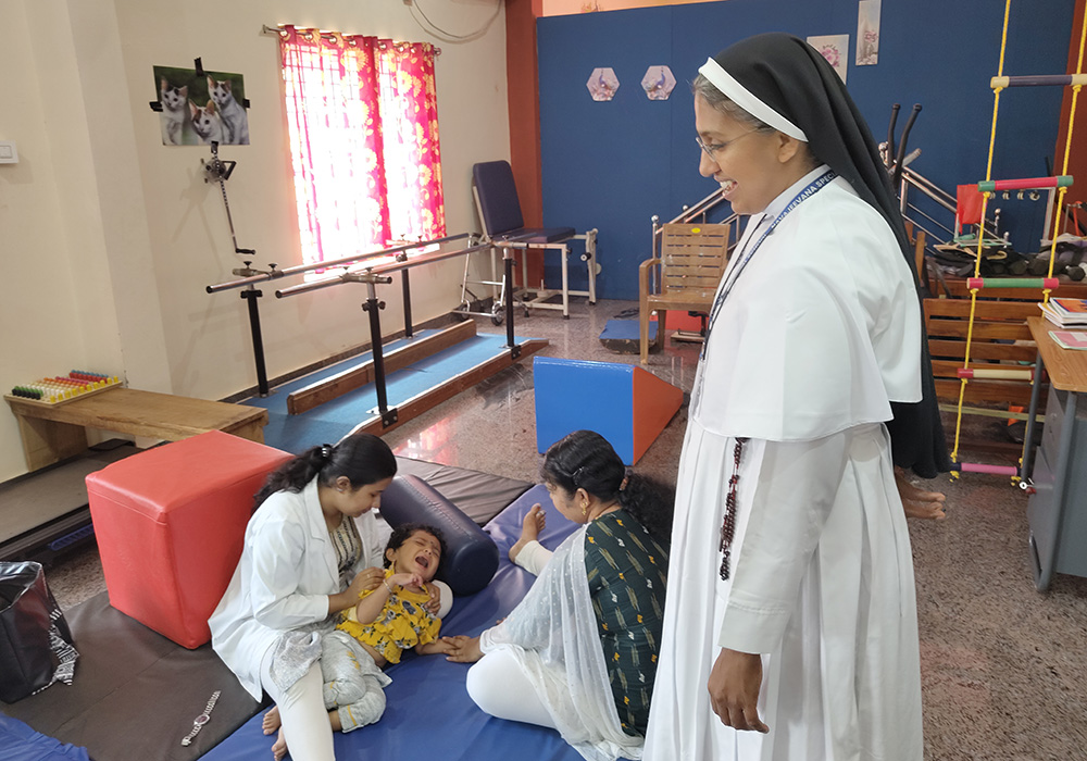 Sr. Mareena Mathew, a Franciscan Clarist nun, is pictured with a therapist and parent Keerthi Ramakrishnan, as they discuss physiotherapy at Navajeevana Endosulfan Special School in Bedrampalla, Kasaragod District, in Kerala, India. Ramakrishnan's son Kashi, also pictured, attends the school. (George Kommattam)