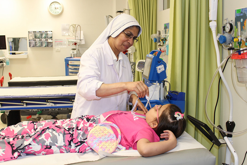 Charity Sr. Felicita Pohkynteng checks the temperature of a young patient at Caritas Baby Hospital Bethlehem in the West Bank. (Courtesy of Caritas Baby Hospital/Marian Nasser)