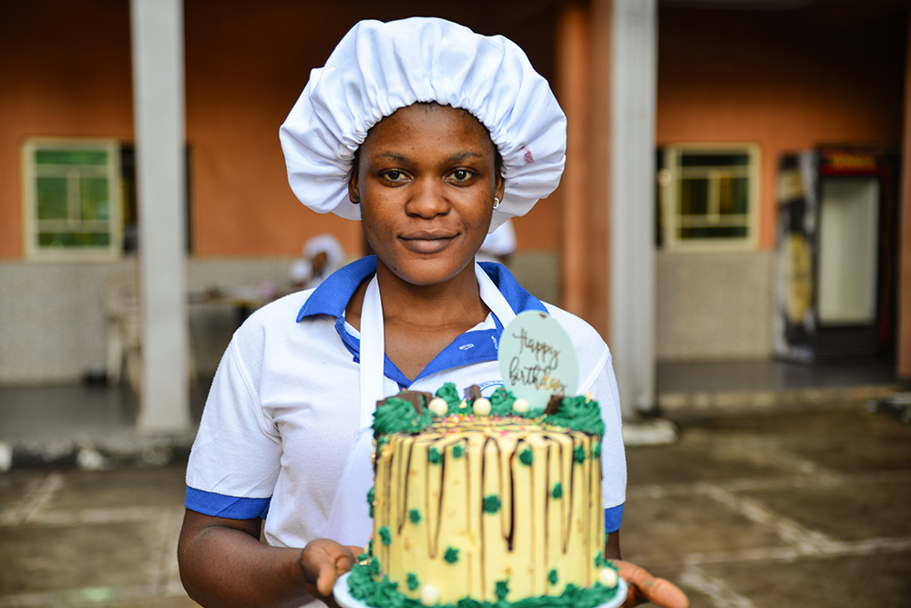 A student at the Divino Amore Vocational Institute in Nigeria holds a cake she made after a baking session. (Patrick Egwu)