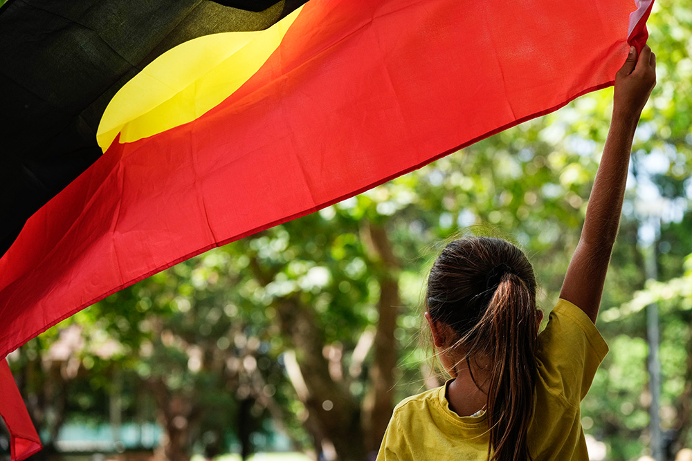 A young girl holds an Aboriginal flag at an Indigenous Australians protest during Australia Day in Sydney Jan. 26, 2024. (AP/Rick Rycroft)