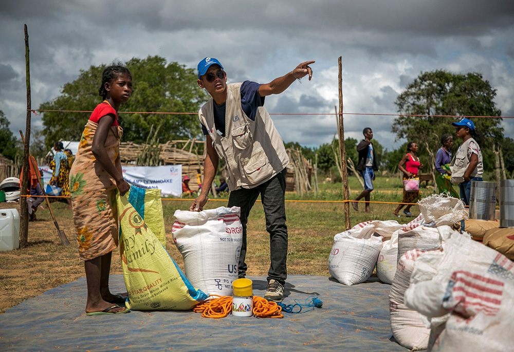 Un trabajador de Catholic Relief Services ayuda a una joven en un área de distribución de alimentos en la aldea de Marojela, ubicada en la comuna de Marolinta, en el distrito de Beloha, al sur de Madagascar. Ese día, 416 personas de seis aldeas recibieron alimentos. En los últimos años, la región sur de Madagascar se ha visto afectada por sequías recurrentes. (OSV News/Cortesía de Catholic Relief Services/Jim Stipe)