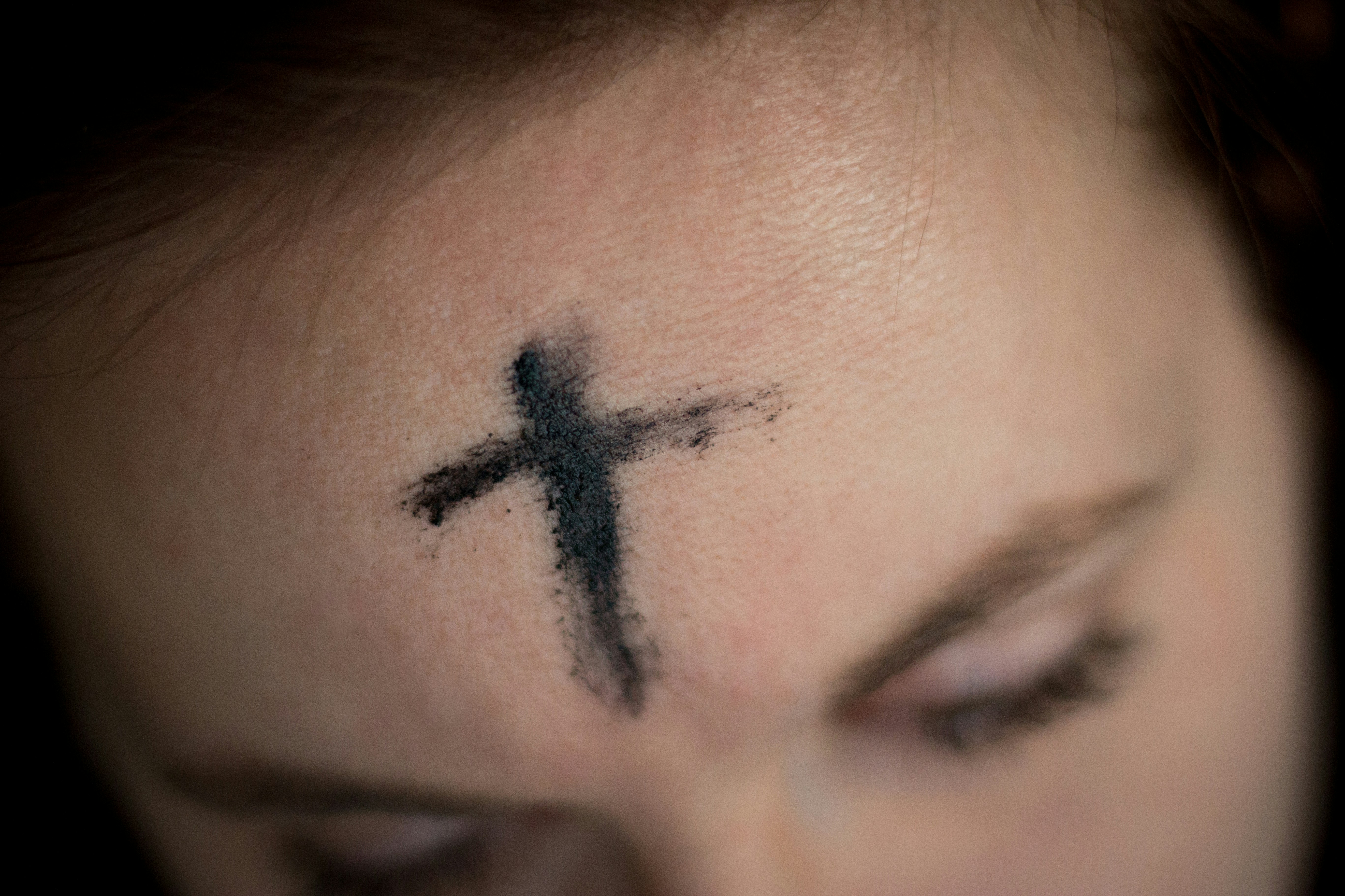 A photo illustration features a close-up of ashes on a woman's forehead. (Unsplash/Ahna Ziegler)