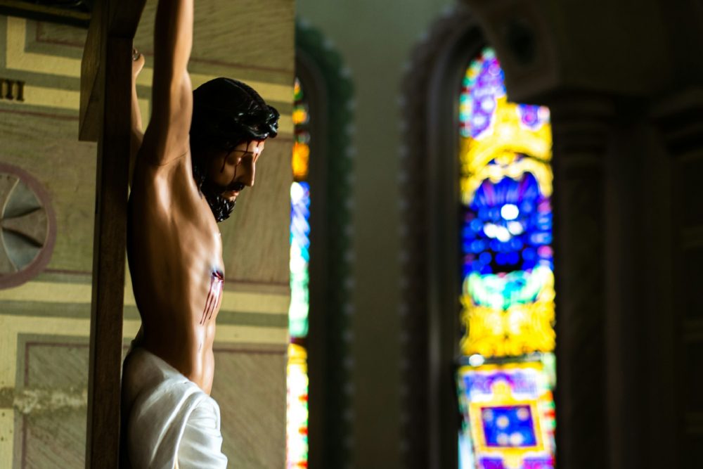 Cropped photo of Jesus Christ on a crucfix with out-of-focus stained glass in the background at at Holy Sacrament Church in Itajai, Brazil. 