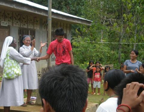 Missionary Benedictine Sr. Edita Eslopor and an African fellow sister distribute school supplies in a village in the rural Philippines. (Courtesy of Rural Missionaries of the Philippines)