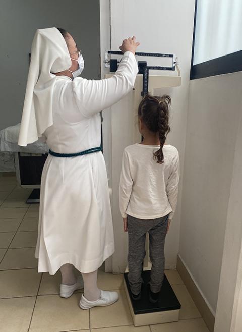 Josephine Sr. Eloide Zavala weighs a migrant child at the CAFEMIN shelter in Mexico City, Aug. 24. With increasing problems in places such as Venezuela, Nicaragua and Haiti, migrants fleeing economic and political woes are facing backlash but find a warm welcome at shelters run by Catholic religious congregations. (GSR photo/Rhina Guidos)