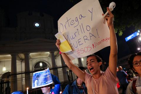 Un nicaragüense exiliado en Costa Rica sostiene un cartel que dice: ¡Fuera Ortega y Murillo! #SOSNicaragua, durante la Vigilia de Fe y Libertad frente a la Catedral Metropolitana de San José, Costa Rica, el 19 de agosto de 2022, para protestar contra la detención del obispo nicaragüense Rolando Álvarez, de Matagalpa, por parte de autoridades nicaragüenses.