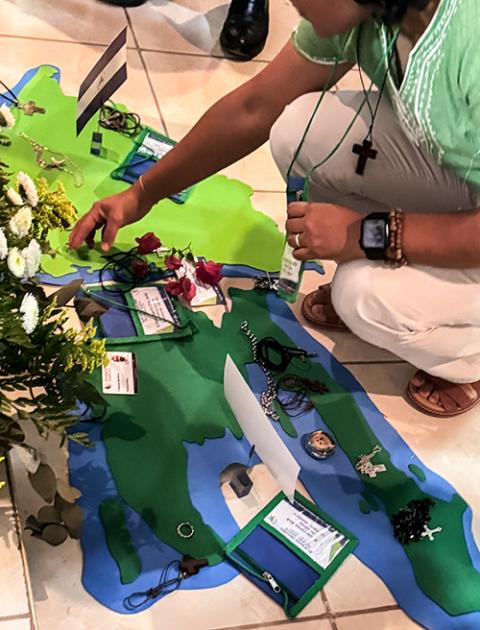 A member of the CLAR places her crucifix on top of a piece of felt in the shape of Haiti in front of an altar before Mass begins at the Catholic University campus in Las Tres Rosas, Honduras, April 18. (GSR photo/Rhina Guidos)