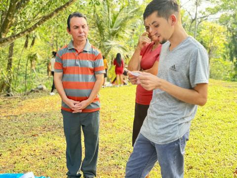 Jóvenes, acompañados por Julio Rivera, izquierda, un sobreviviente de la masacre del río Sumpul, leen un relato el 27 de abril 2024 en Arcatao, El Salvador, para aprender sobre la emboscada y el asesinato de más de 600 campesinos en 1980. (Foto: Rhina Guidos/GSR)